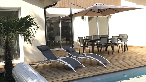 Una casa moderna con piscina, mobiliario exterior y un patio.