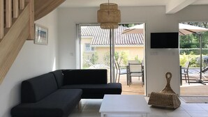 Una sala de estar moderna con una escalera de madera, un sofá seccional negro, una mesa de centro blanca y una lámpara colgante azul grande.