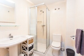 Une salle de bain avec une douche à parois de verre, un lavabo blanc et des toilettes.