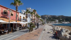 A seaside promenade with outdoor seating, palm trees, and buildings along the coast. - Holiday rental Penthouse Javea (Javea / Xàbia)