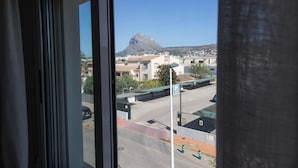 A view through a window of a street with buildings, a mountain, and a clear sky. - Holiday rental Penthouse Javea (Javea / Xàbia)