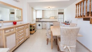 A spacious kitchen with a dining area, wooden cabinets, a washing machine, and a dining table with wicker chairs. - Holiday rental Penthouse Javea (Javea / Xàbia)