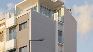 Ein modernes Gebäude mit flachem Dach, großen Fenstern und einem Balkon mit Glasgeländern.
