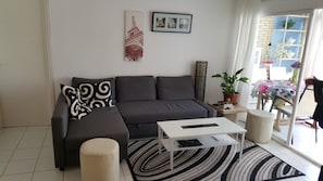 A modern living room with a grey sectional sofa, a white coffee table, and a black and white striped rug. There is a potted plant on a side table and a framed picture of flowers on the wall. - Seafront Charming Albir Apt (next To Altea, Benidorm); Wifi, AC, Golf, Sea Views (L'Alfàs del Pi)