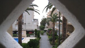 Une cour avec un sentier, des palmiers, une piscine et des bâtiments en arrière-plan.