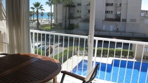 Un balcon donnant sur une piscine, avec une table et des chaises.