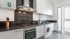 A modern kitchen with a Bosch oven, a built-in washing machine, and a stainless steel range hood. - Rodamar I, the promenade, the beach and a sea view (Funchal)