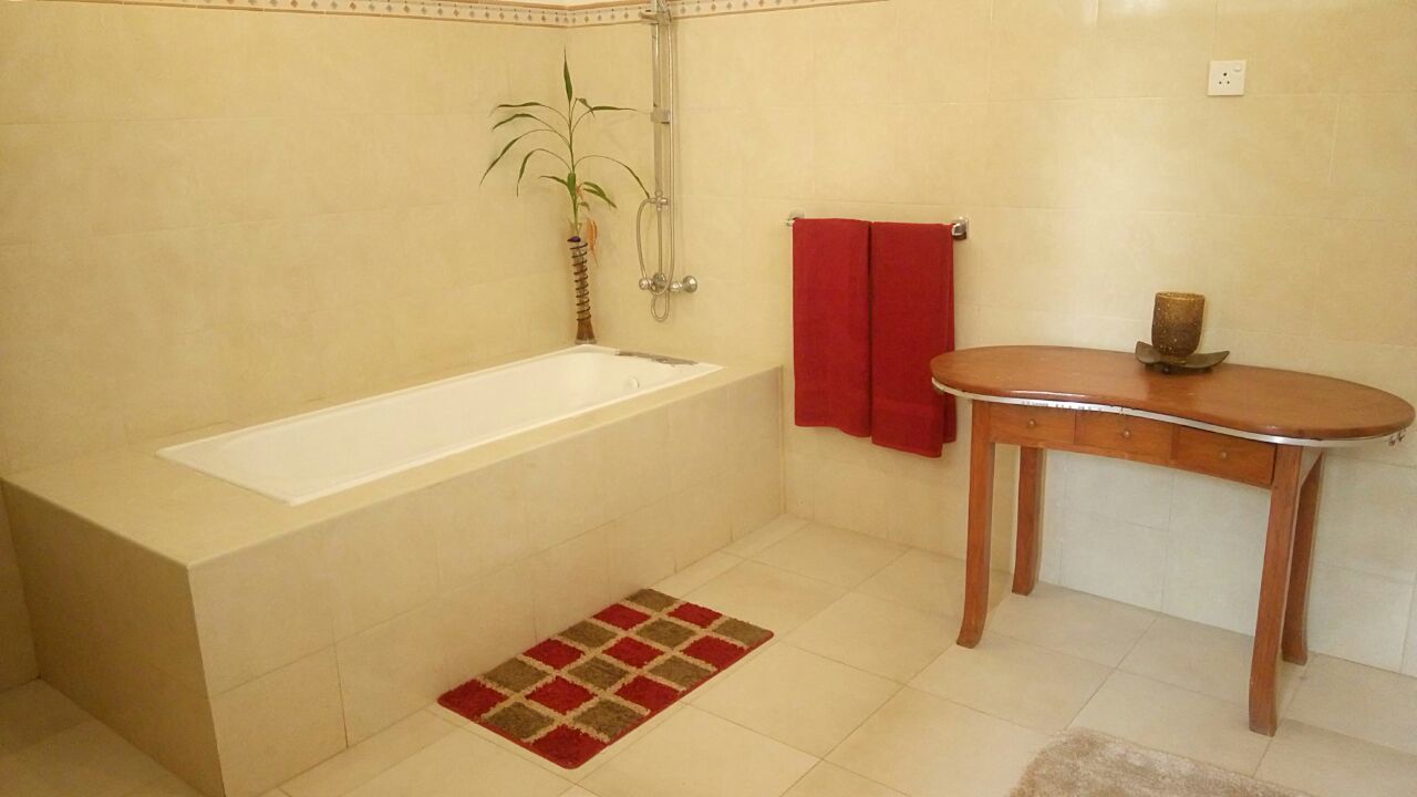 A bathroom with a bathtub, a wooden vanity, a red towel, and a small plant.