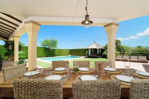 Enjoy a formal dining experience on the covered patio, surrounded by comfortable seating and a serene pool view.
