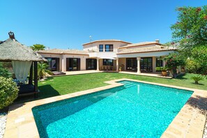 Enjoy a refreshing swim in the backyard pool or relax under the thatched-roof gazebo.