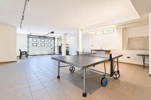 A spacious room with a ping pong table, a whiteboard, and a large window.