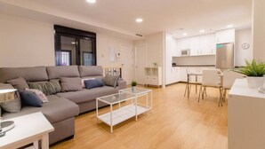 Una sala moderna con un sofá, una mesa de centro y una zona de comedor con sillas y una mesa.
