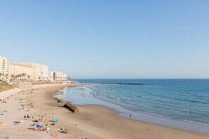 A beach with a sandy shore, a few people, and buildings in the background.