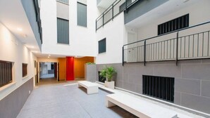 Un patio interior moderno con una zona de estar central, una chimenea y una escalera que conduce a un nivel superior.