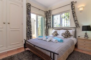 A bedroom with a bed, curtains, a nightstand, a lamp, and a window with a view.