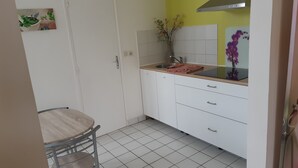 Eine kompakte Küche mit weißen Schränken, einem Spülbecken und einem kleinen Esstisch mit Stühlen.