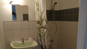 Ein Badezimmer mit Waschbecken, Spiegel, Dusche und gefliesten Wänden.