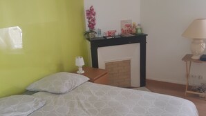 Ein Schlafzimmer mit Bett, Nachttisch, Lampe, Kamin und einem Wandbild.