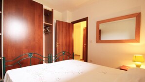 Une chambre à coucher avec un lit, une armoire en bois, un miroir et une table de chevet avec une lampe.