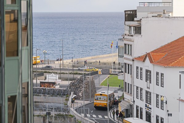 Une rue côtière avec un autobus, des bâtiments et une vue sur la mer.