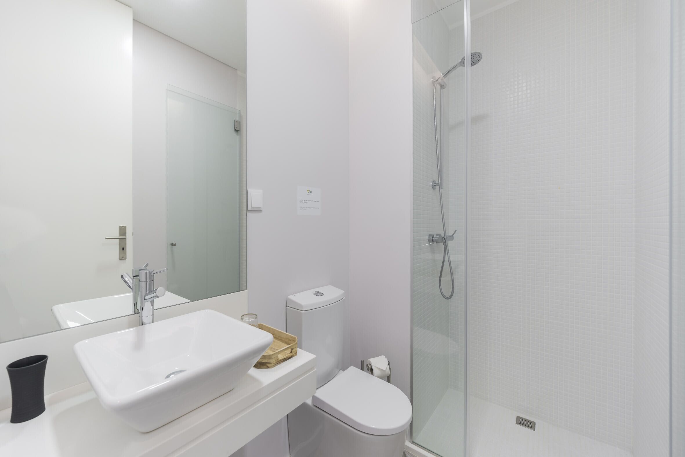 Ein modernes Badezimmer mit einer begehbaren Glasdusche, einem weißen Waschbecken und einer Toilette.
