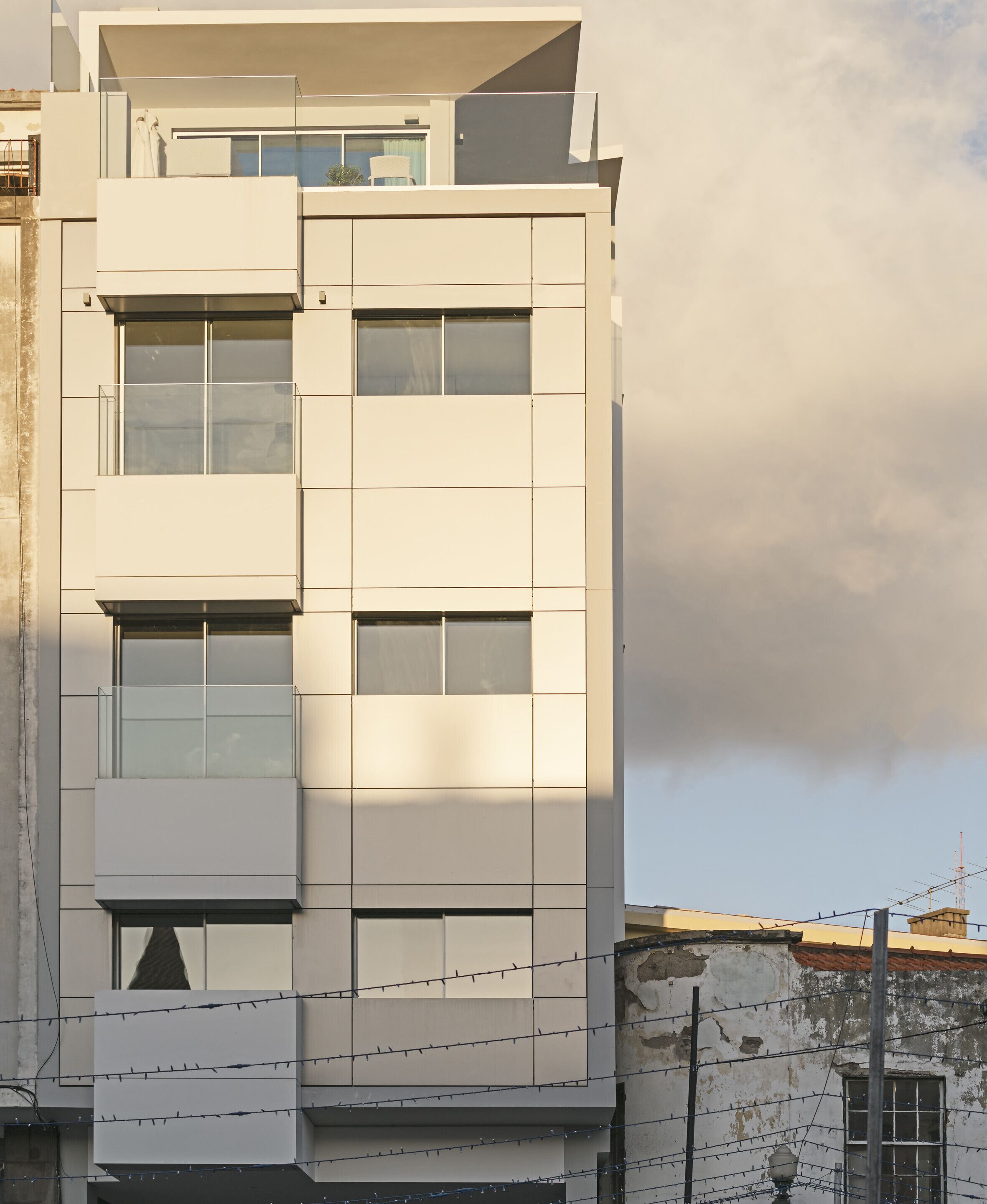 Een meerlaags gebouw met een modern architectonisch ontwerp, met grote ramen en een balkon op de bovenste verdieping.