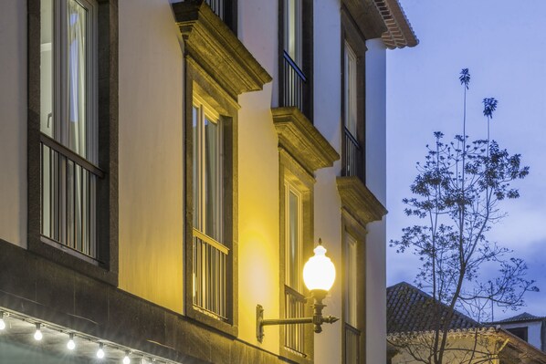 Une façade d’immeuble avec de grandes fenêtres, un lampadaire et un arbre.