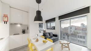 A modern apartment with a kitchen, dining area, and a large window offering a city view.
