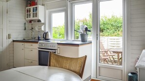 Cocina compacta con estufa, lavamanos y ventana que da a un jardín.