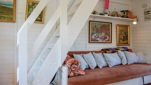 Un salón acogedor con un sofá de cuero marrón, paredes blancas y una escalera blanca.