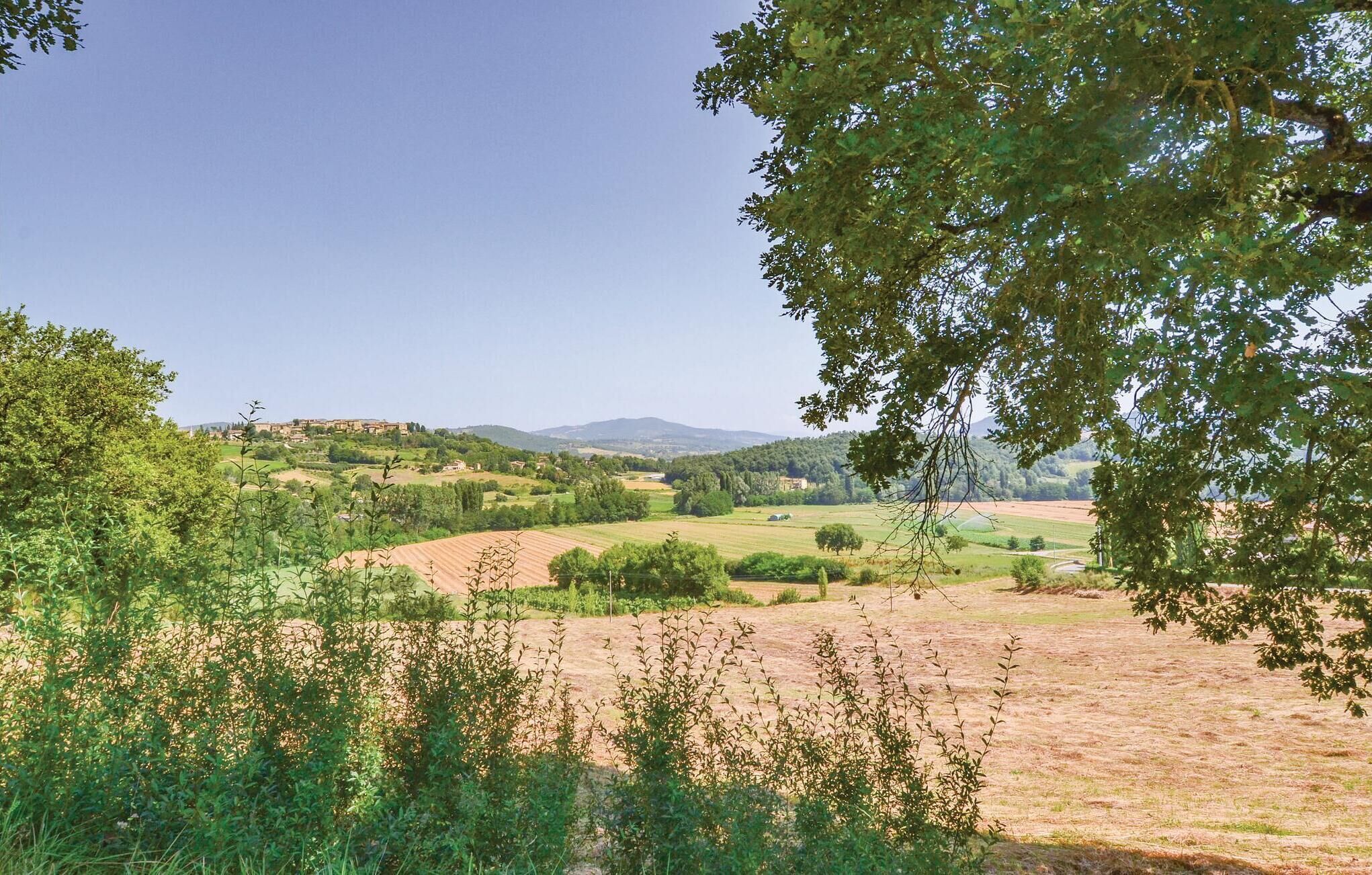 A rural landscape with rolling hills, fields, and a distant village.