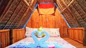 Un dormitorio acogedor en el ático, con techo inclinado, paredes de madera y una cama con colcha estampada.