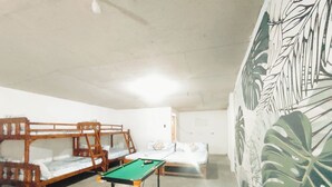 Una habitación con literas, una mesa de billar y una planta grande.