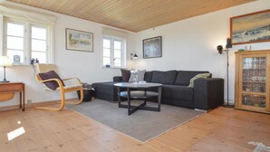 A cozy living room with a wooden floor, a grey sofa, a round coffee table, a rocking chair, and a cabinet with glass doors. - Lovely home in Vordingborg with WiFi (Vordingborg)