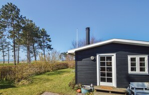 Een klein huisje met schoorsteen, een deur met raam en een bankje ervoor.