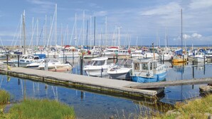 Un port esportiu amb nombroses embarcacions amarrades, aigua tranquil·la i cel serè.