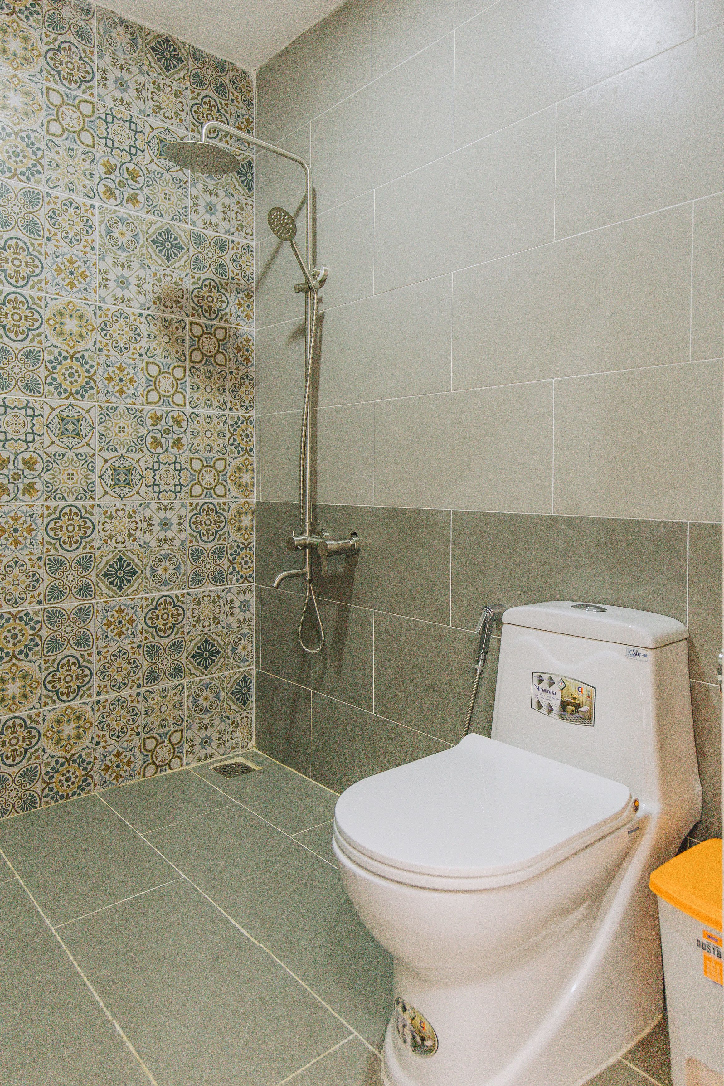 A bathroom with a shower, toilet, and patterned tiles.