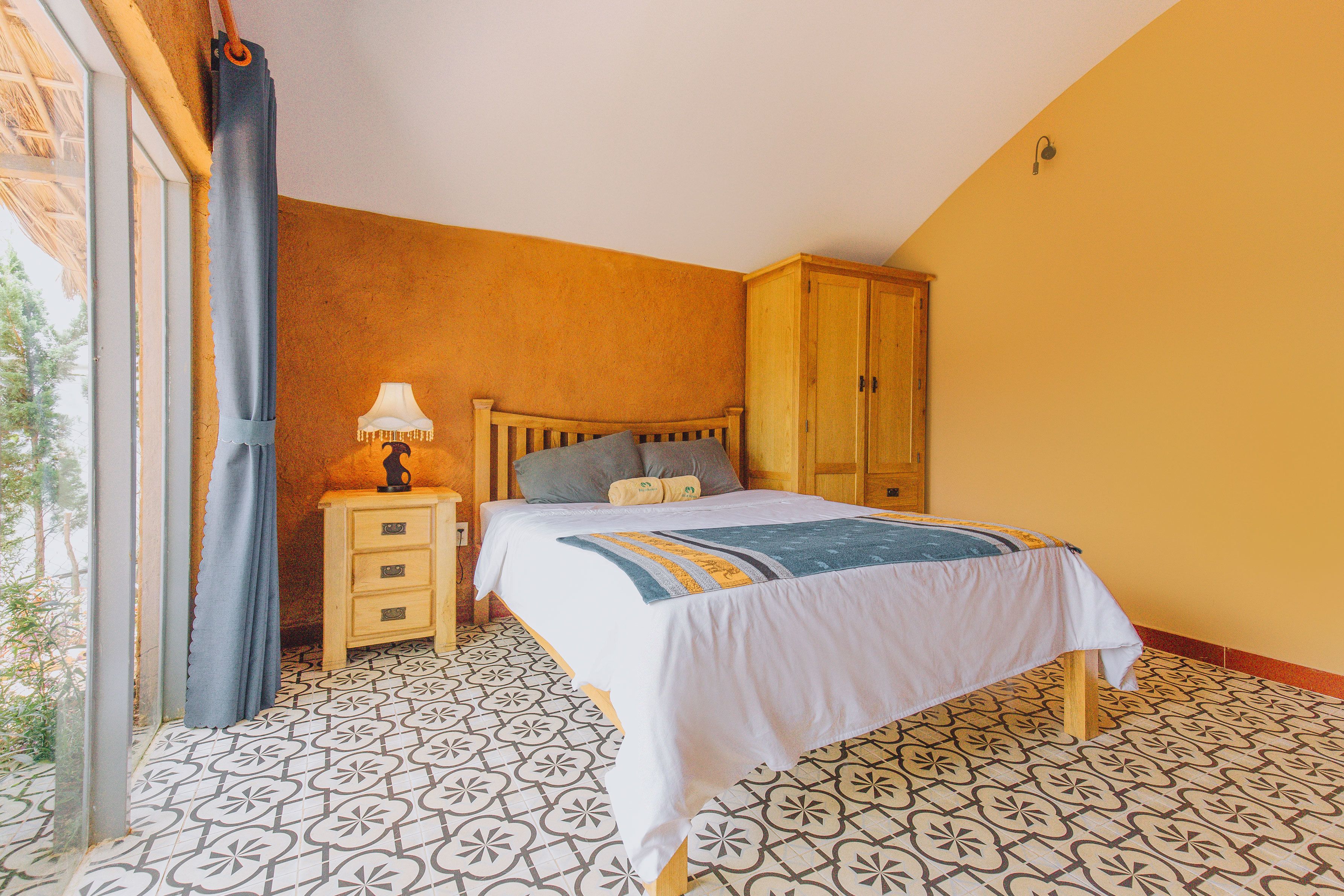 A bedroom with a bed, a nightstand, a lamp, and a wardrobe.