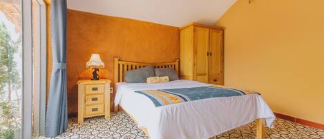A bedroom with a bed, a nightstand, a lamp, and a wardrobe.