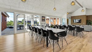 Ein geräumiger Essbereich mit mehreren Tischen und Stühlen, großen Fenstern und einem modernen Interieur.