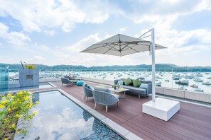 Una terrazza sul tetto con piscina, area relax e vista sulle barche in acqua.