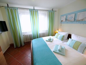 Habitación de hotel con cama, televisor y ventana con cortinas.