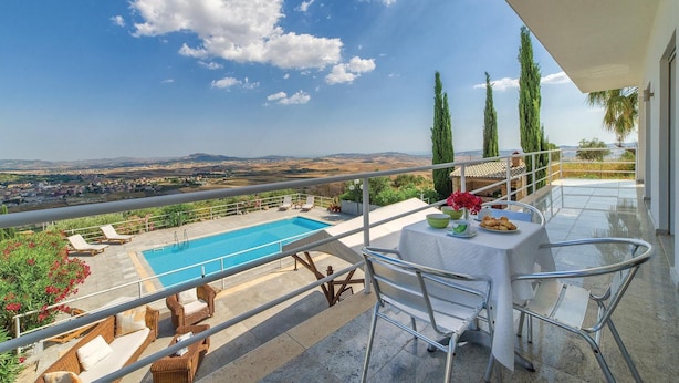 A balcony with a pool, outdoor seating, and a table with a vase of flowers.