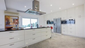 A modern kitchen with white cabinetry, stainless steel appliances, and a large window providing natural light.