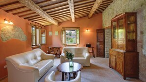 A cozy living room with a stone wall, wooden beams, a fireplace, and a large wooden cabinet. - Gorgeous home in Barchi PU with private swimming pool, can be inside or outside (Barchi PU)