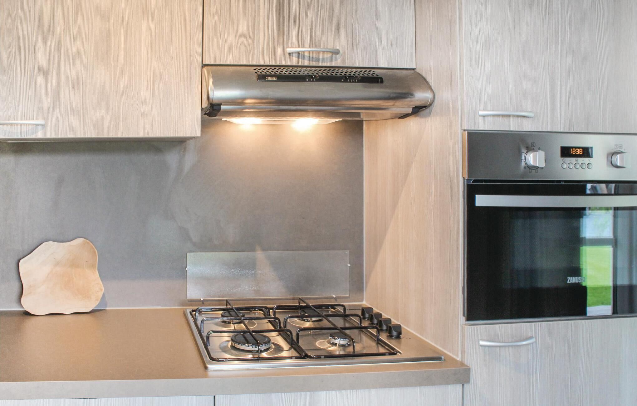 Una cucina moderna con piano cottura a gas, forno integrato e cappa aspirante in acciaio inossidabile.