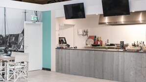 Et moderne køkken med en grå bordplade, rustfrie hvidevarer og udsigt til gaden gennem et stort vindue.
