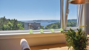 Une vue depuis une fenêtre, avec un plancher en bois, une chaise sur laquelle est posée une serviette et un vase rempli de fleurs.