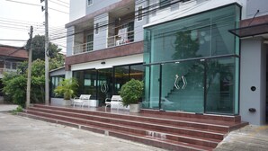 A modern building with a glass facade, a set of outdoor stairs, and a few potted plants. - LOFT Salaya (Phutthamonthon)