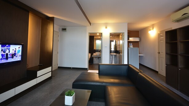 A modern living room with a flat-screen TV, a sofa, and a coffee table. - LOFT Salaya (Phutthamonthon)